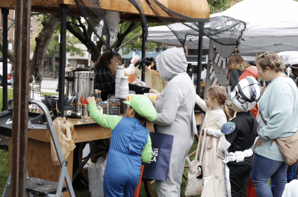 Families and children in Halloween costumes visiting vendors at a fall event in downtown Valparaiso, Indiana.